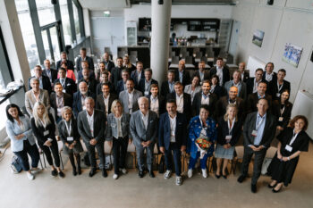 Gesamtes Gruppenfoto, alle tragen Businesskleidung und stehen